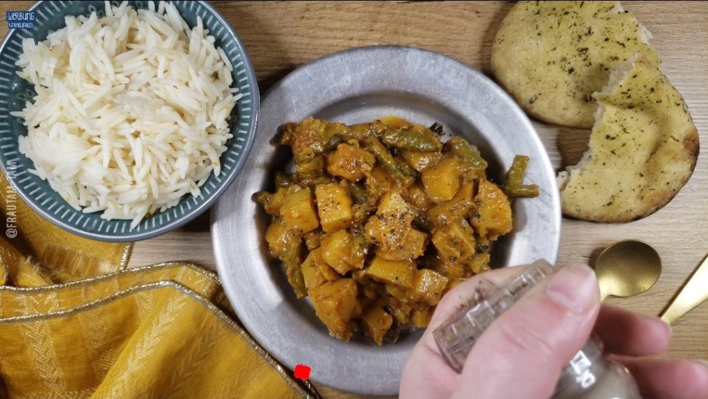 Indisches Kartoffel-Curry zum Servieren mit schwarzem Pfeffer bestreuen.